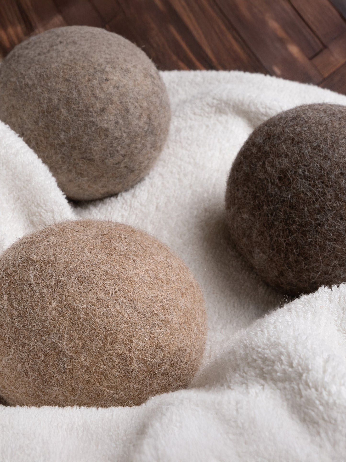 Three brown alpaca dryer balls on a white fabric background
