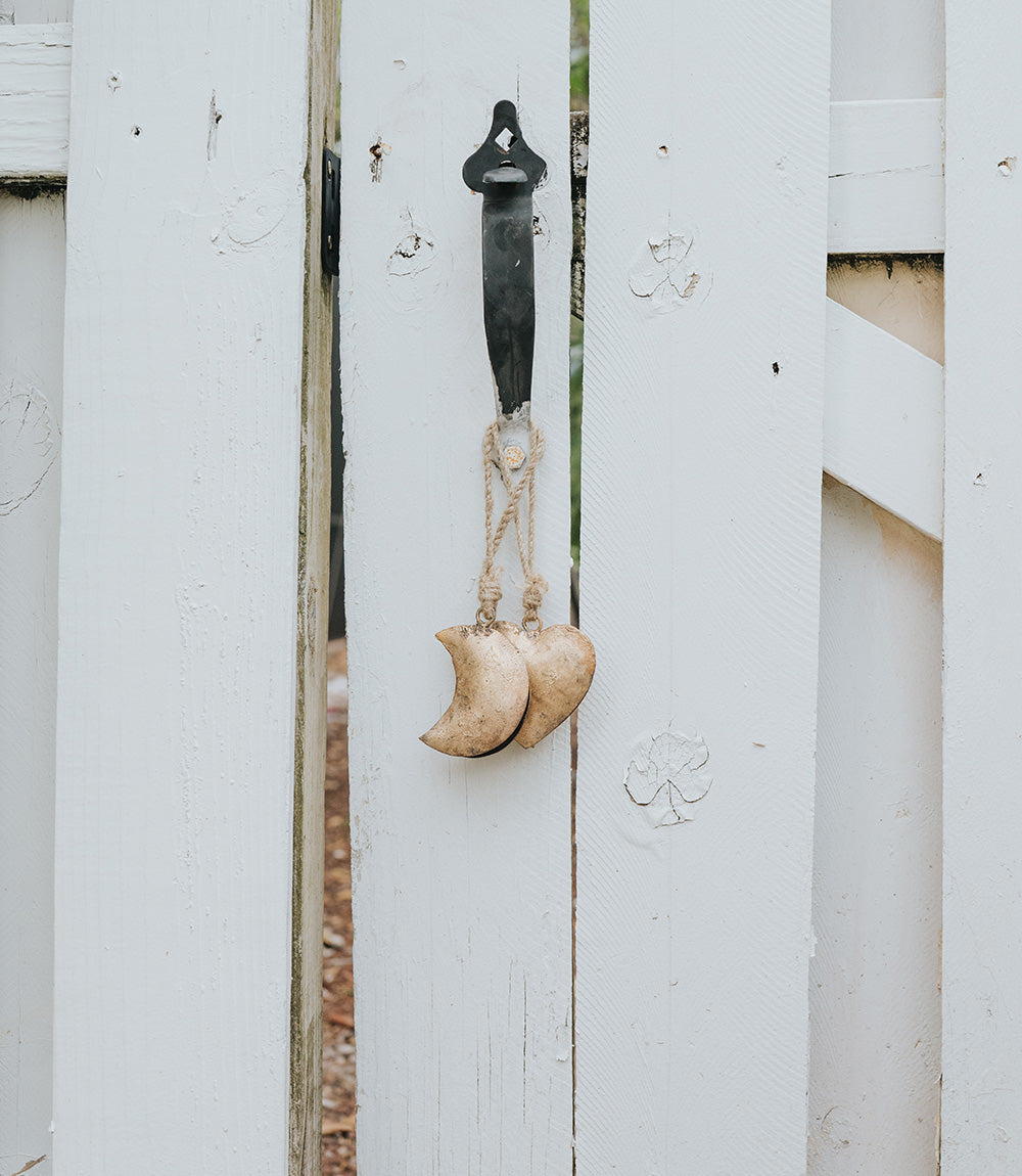 Decorative hook with crescent moon and heart shapes on a white wooden surface