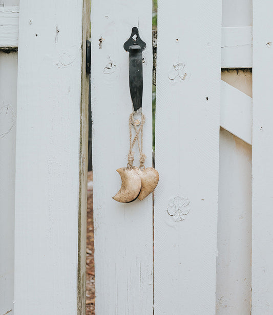 Decorative hook with crescent moon and heart shapes on a white wooden surface