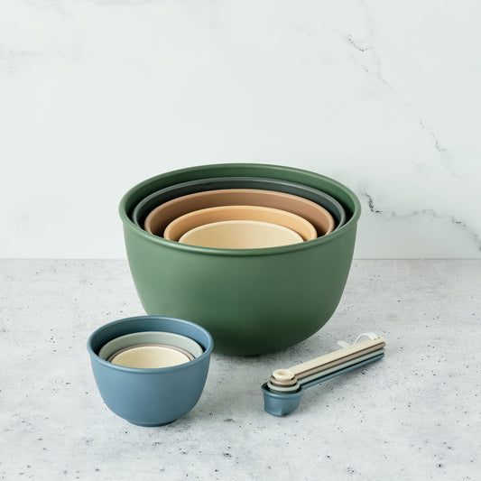 Set of Astrik mixing bowls, measuring cups and spoons in alpine forest (green, beige, and blue) on a light gray surface.