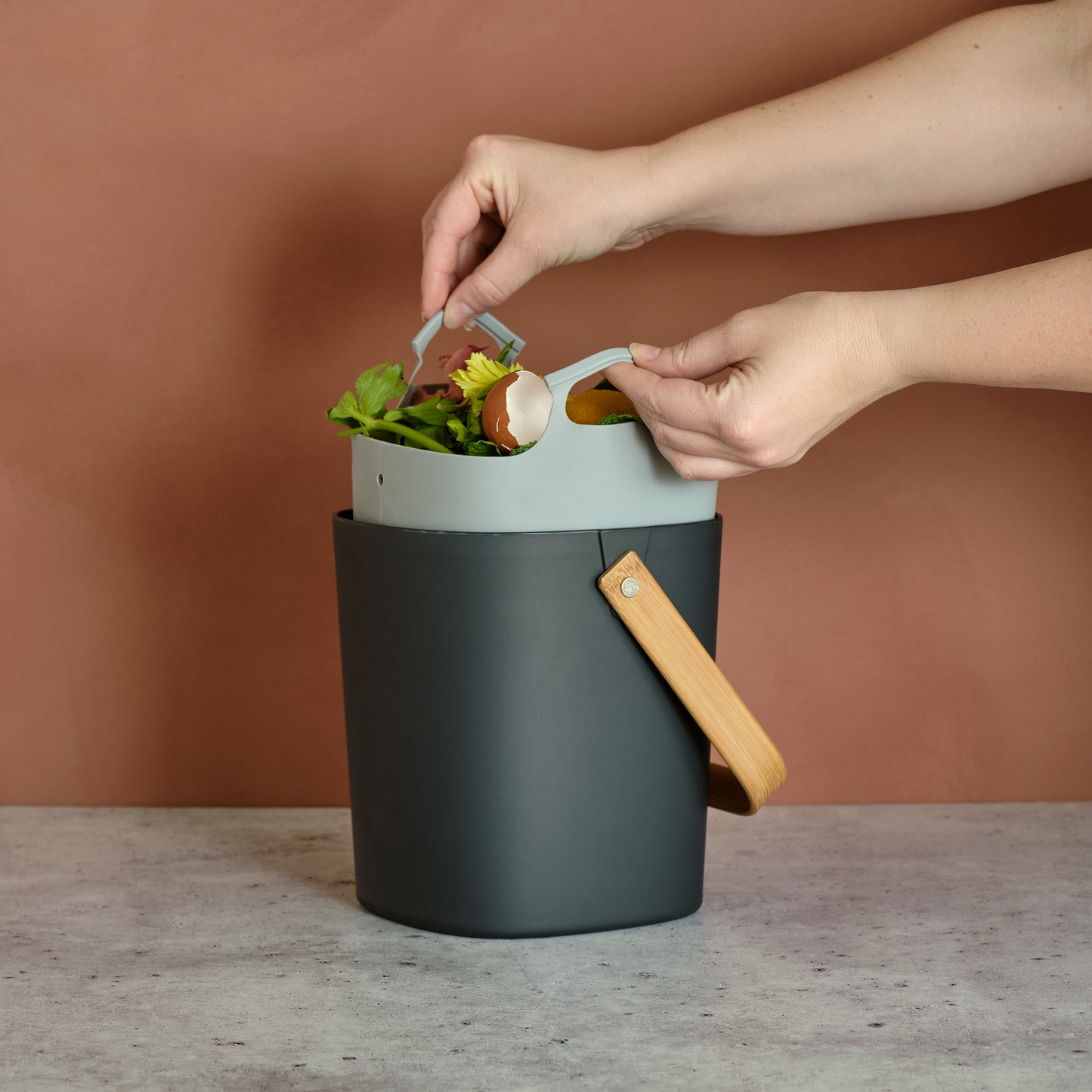 Person using an Astrik Compost Bin with a brown background