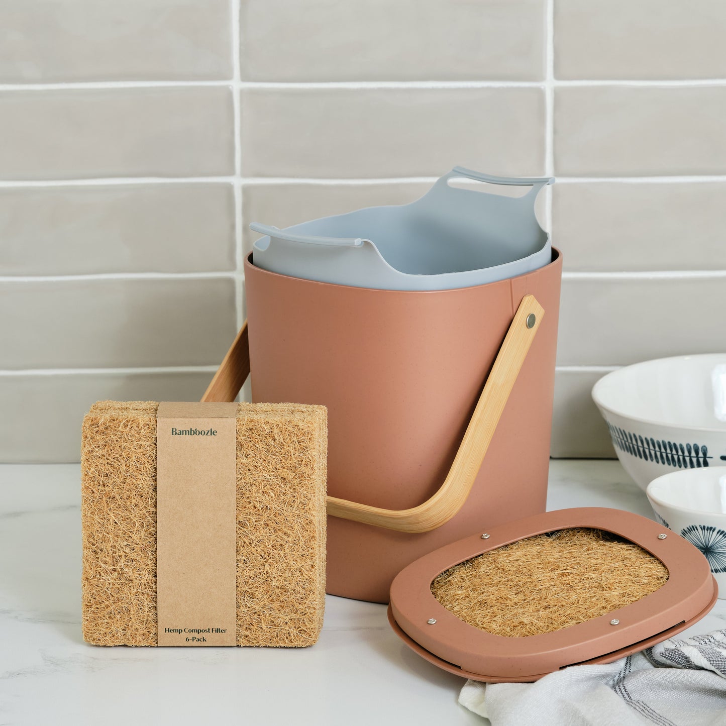 Astrik Kitchen Compost Starter Bundle in terracotta on a tiled wall background.