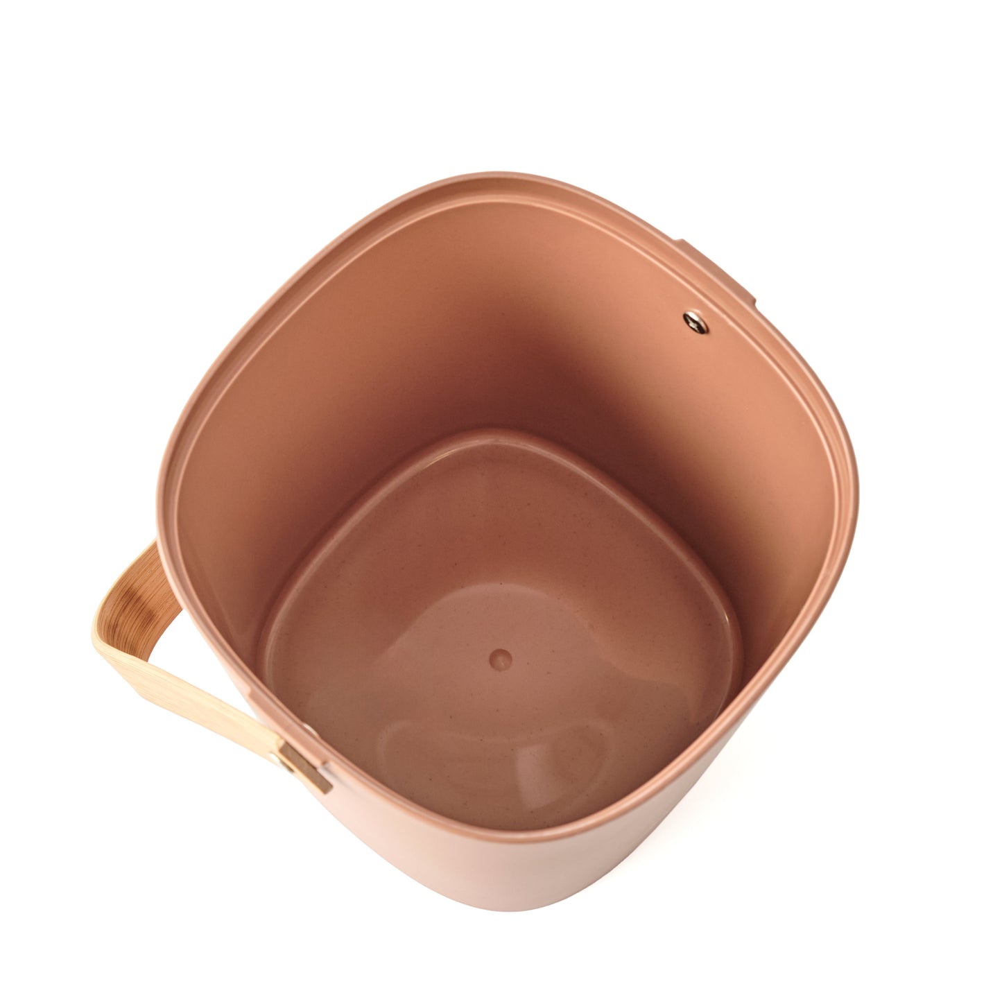 View inside of a terracotta-colored Astrik Compoast Bin made of 100% biodegradable plant-based plastic with a bamboo handle on a white background.