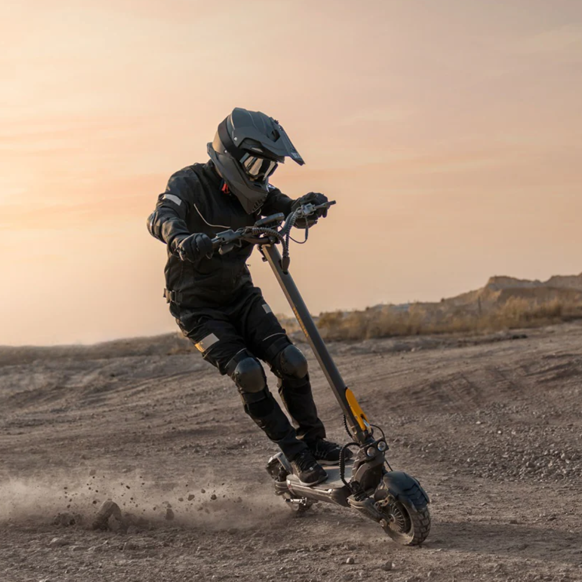 Person riding an AUSUM F1 Max electric scooter in a desert landscape with a sunset sky