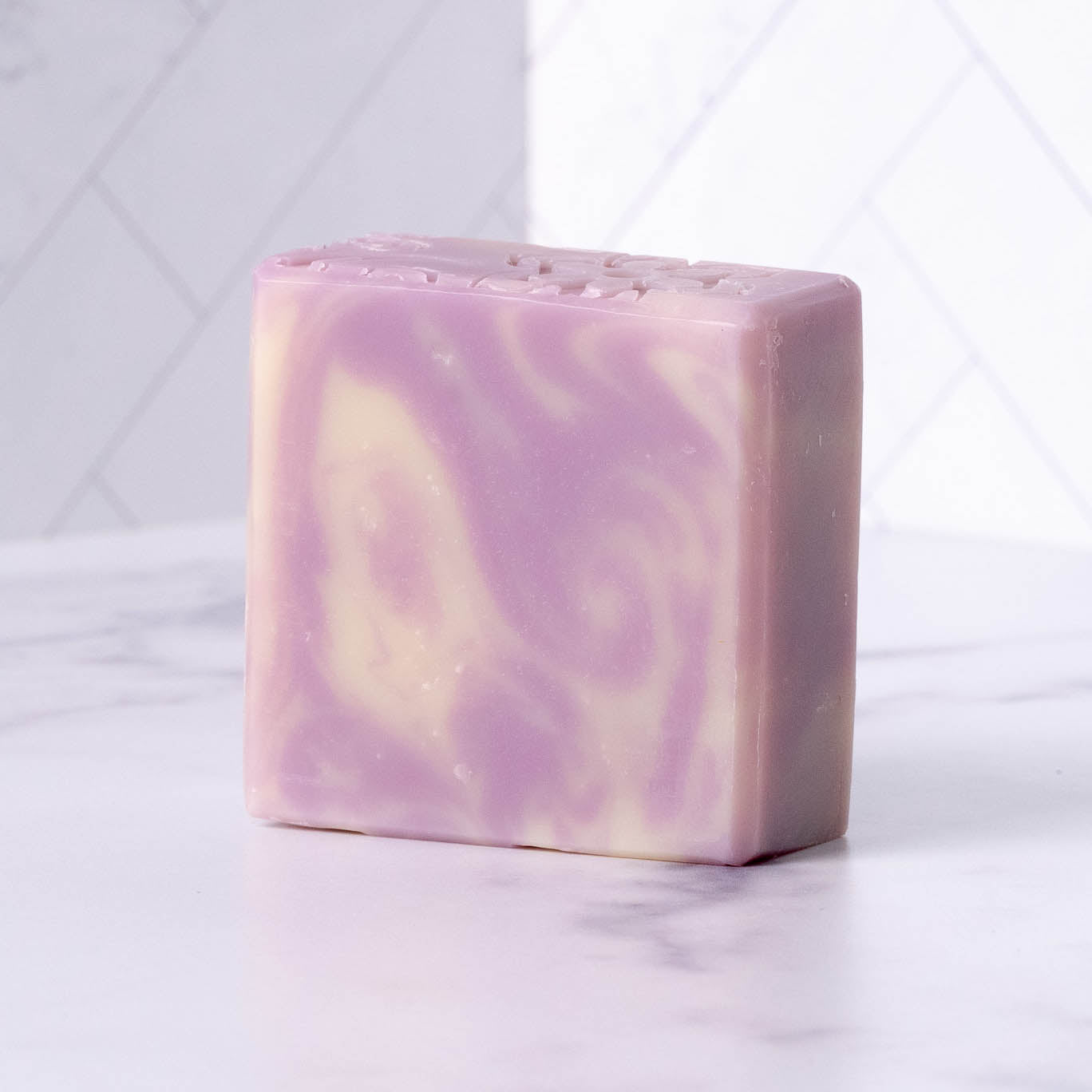 Swirled purple and white lavender soap bar on a light gray background