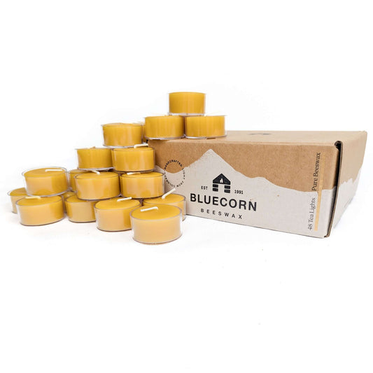 Case of beeswax tea light candles in front of a Bluecorn Beeswax box on a white background