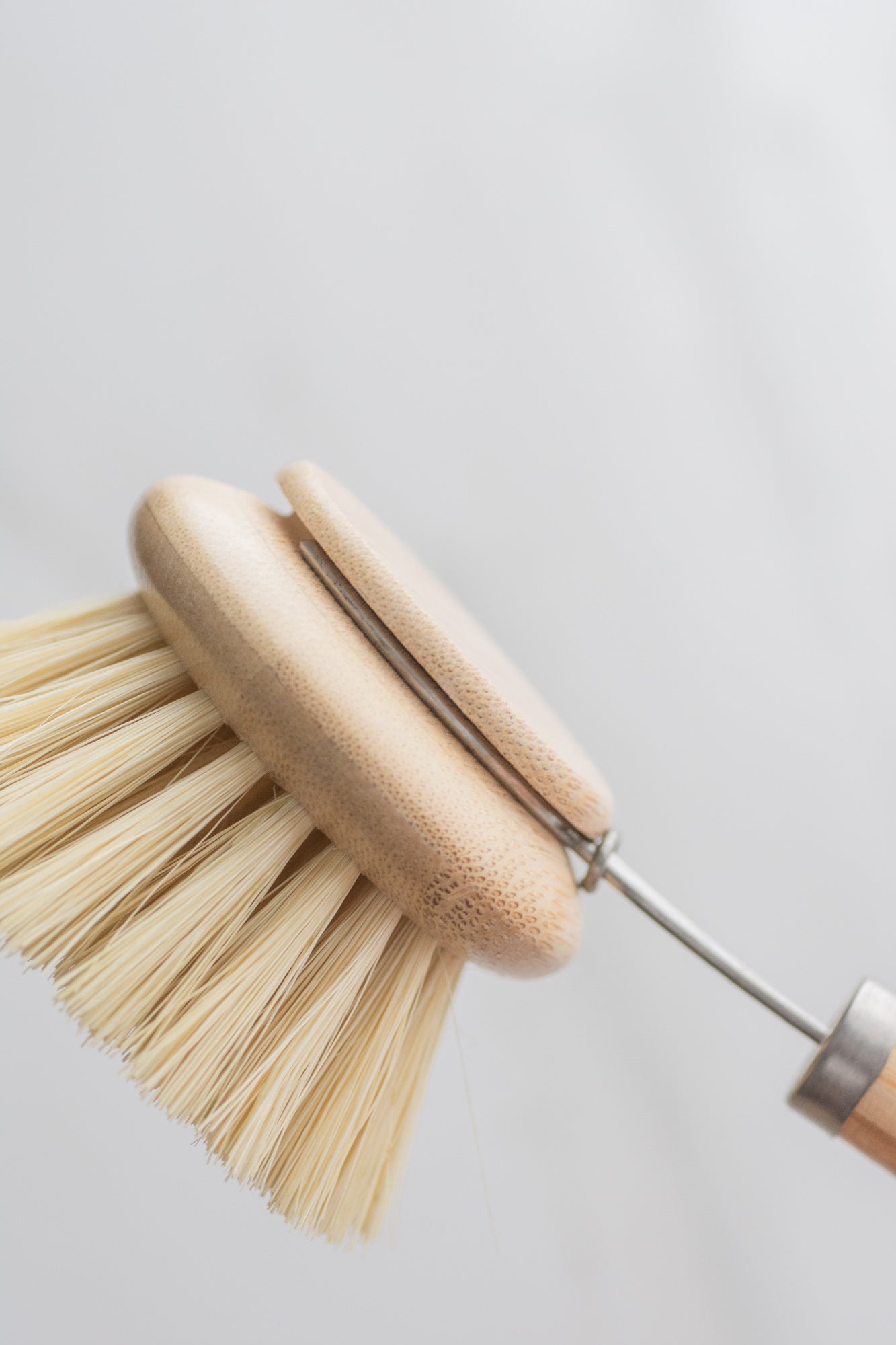 Dishwashing brush with vegan bamboo handle and bristles on a light gray background