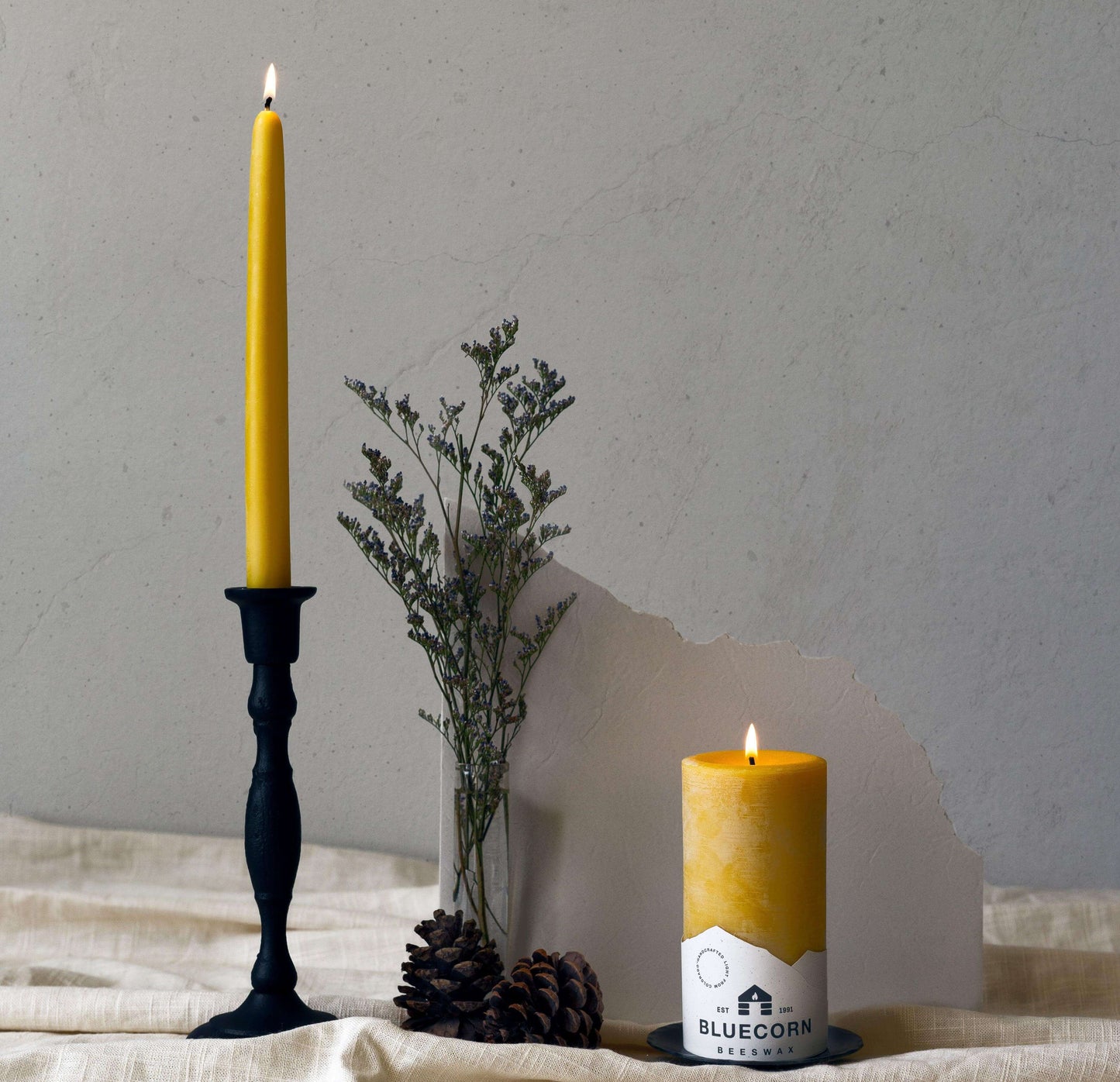 Two yellow candles on a textured surface with a minimal background