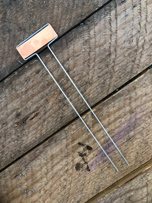 Copper plant label on a wooden surface