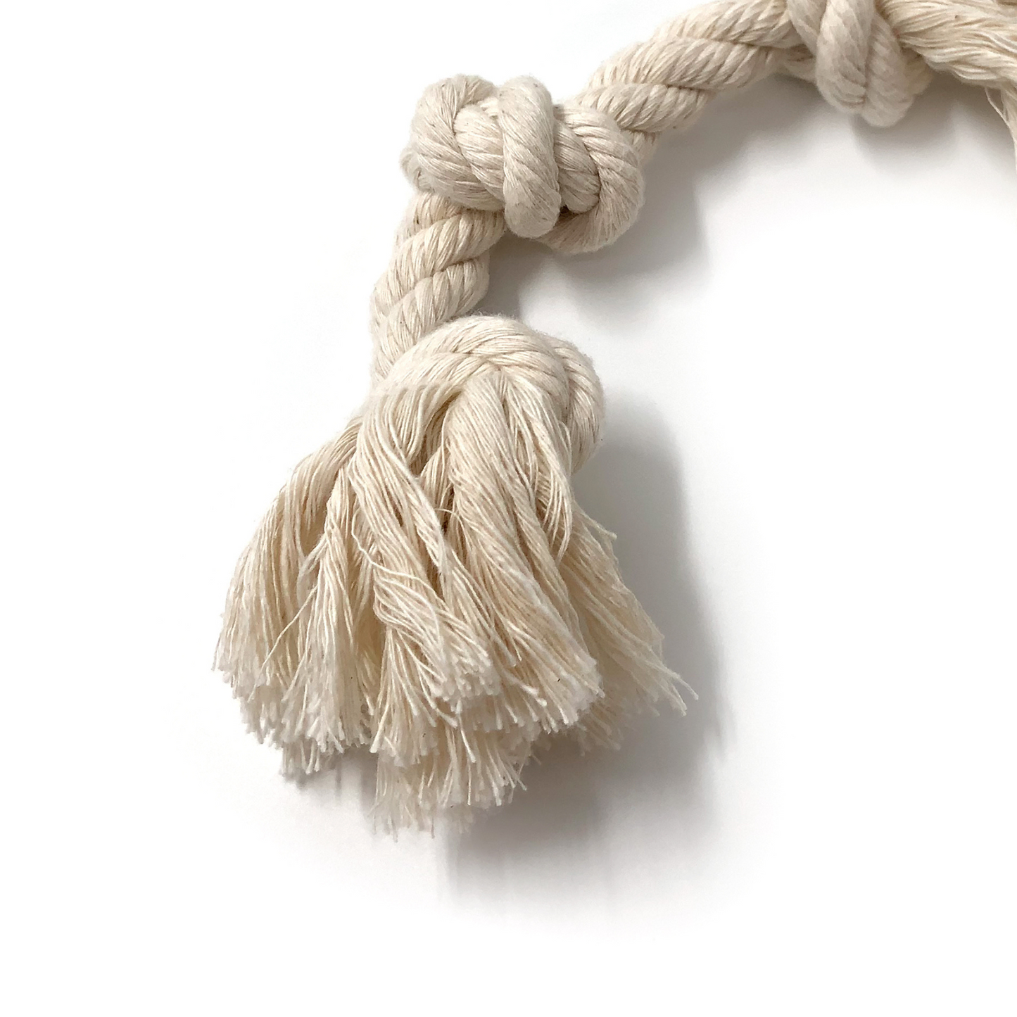 Beige organic cotton dog rope toy with a knot and tassels on a white background