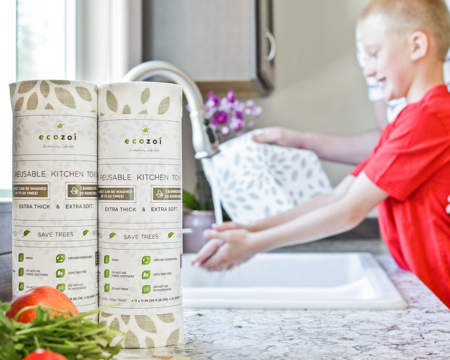 Two packages of ecozoi reusable kitchen towels with a child washing dishes in the background.