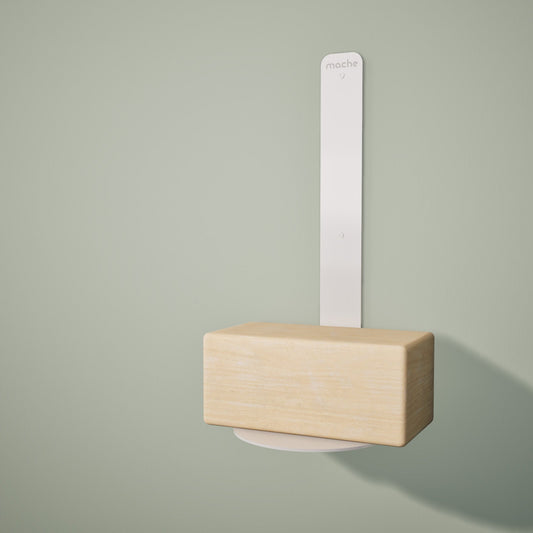 Wooden yoga block resting on a white wall-mounted floating yoga block shelf on a light green background