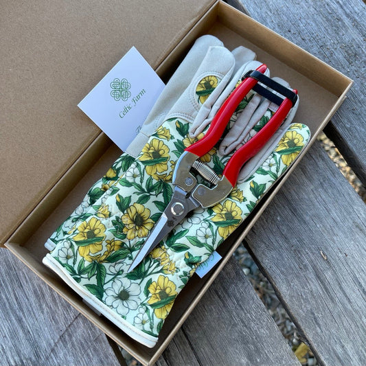 Gardening pruner and floral-patterned gloves inside a cardboard gift box with a visible brand label.