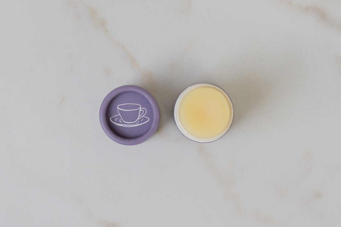 Open tube of No Tox Life SolidSilk Lavender Earl Grey Lip Balm on a marble surface.