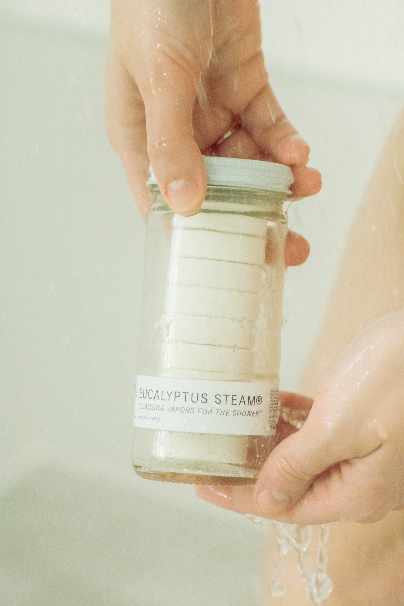 Person holding a jar labeled 'Eucalyptus Steam' with a blurred background