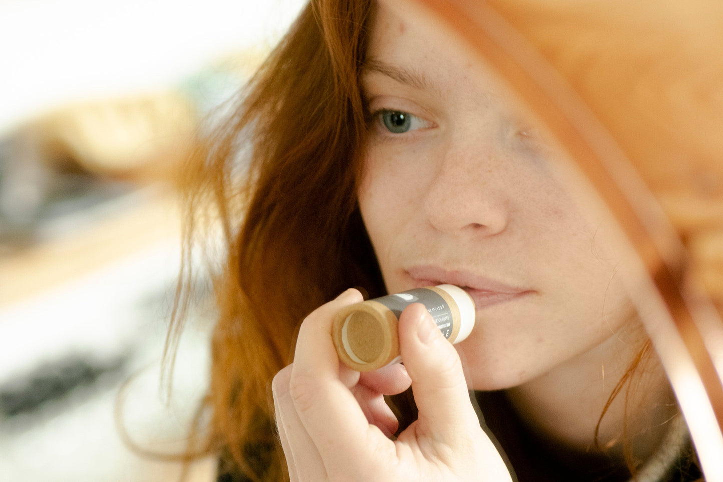 Person applying No Tox Life SoliSilk lip balm outdoors