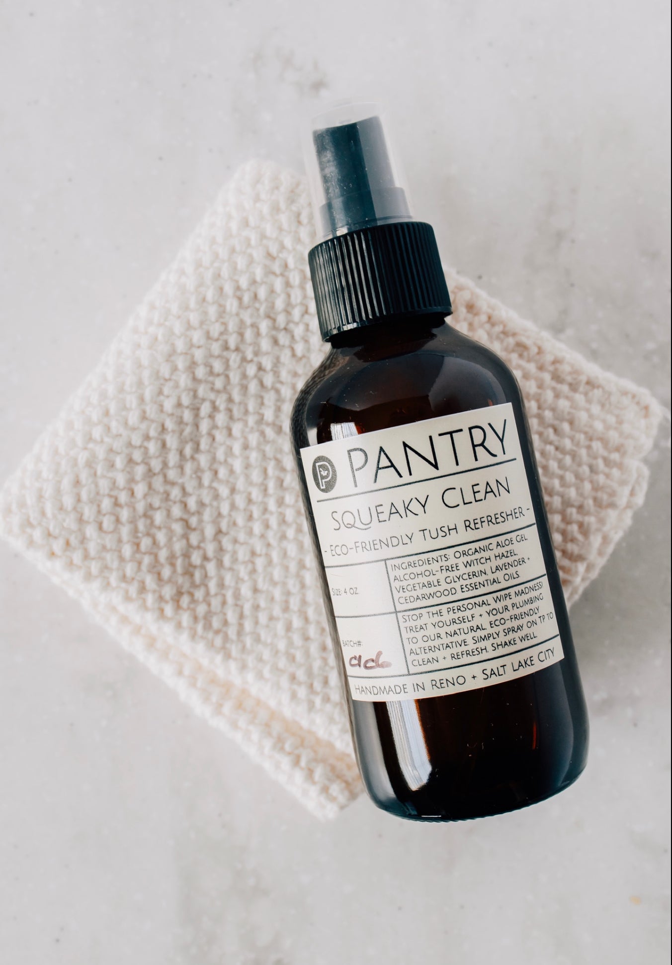Bottle of Pantry Squeaky Clean Eco-Friendly Tush Refresher, resting on a cotton cloth on a white marble surface.