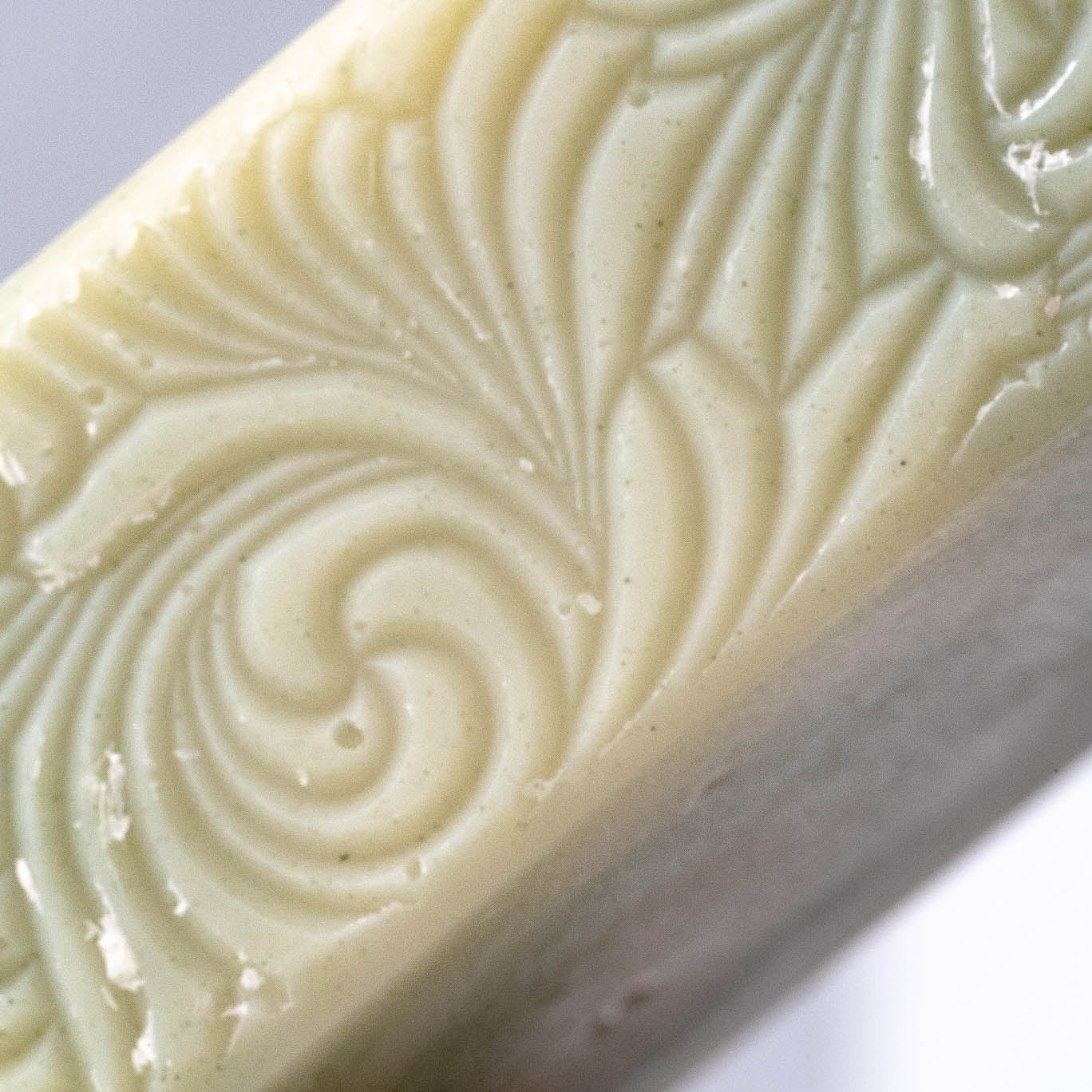 Close-up of a bar of peppermint tea tree soap with a decorative pattern on a light background