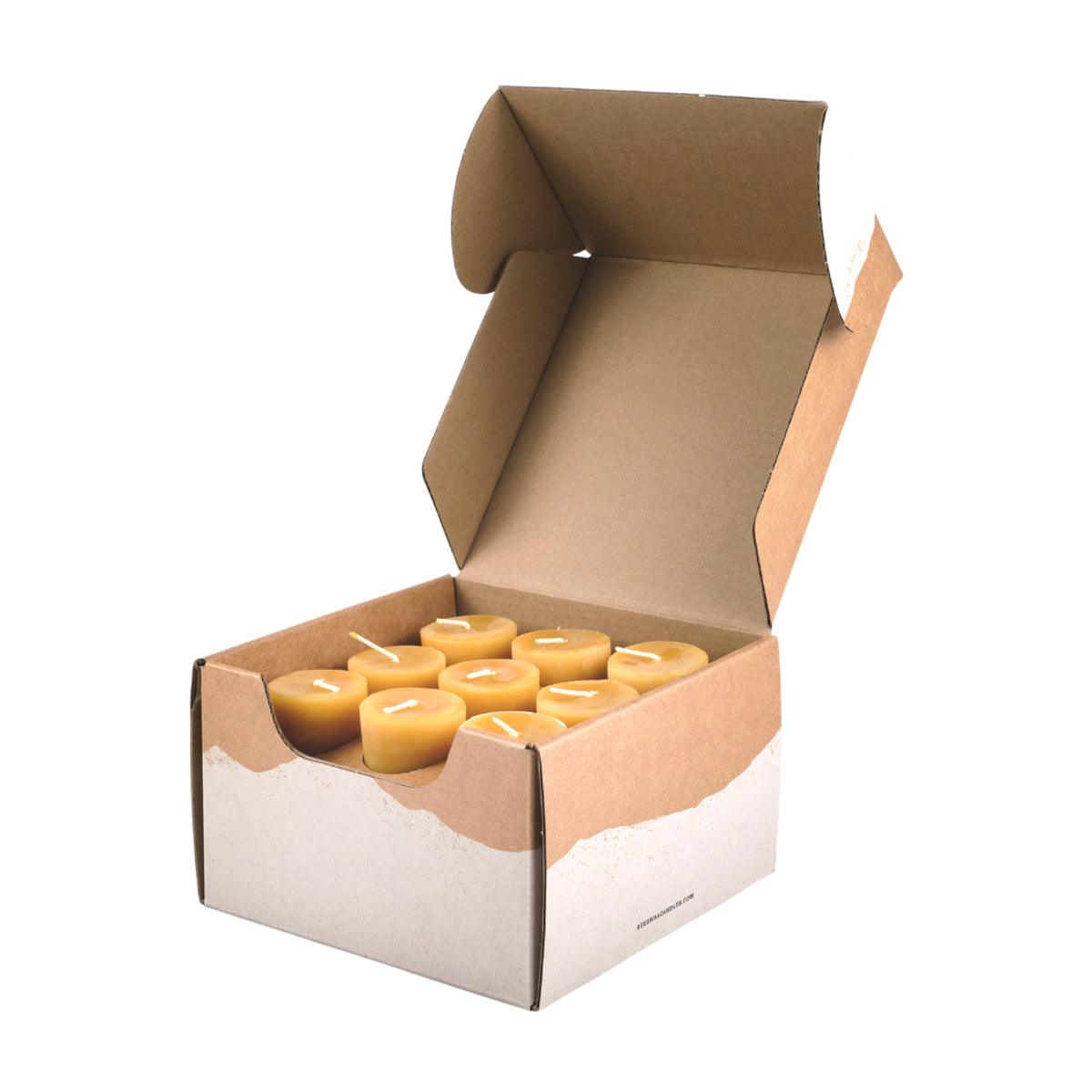 Open cardboard box containing small votive candles on a white background