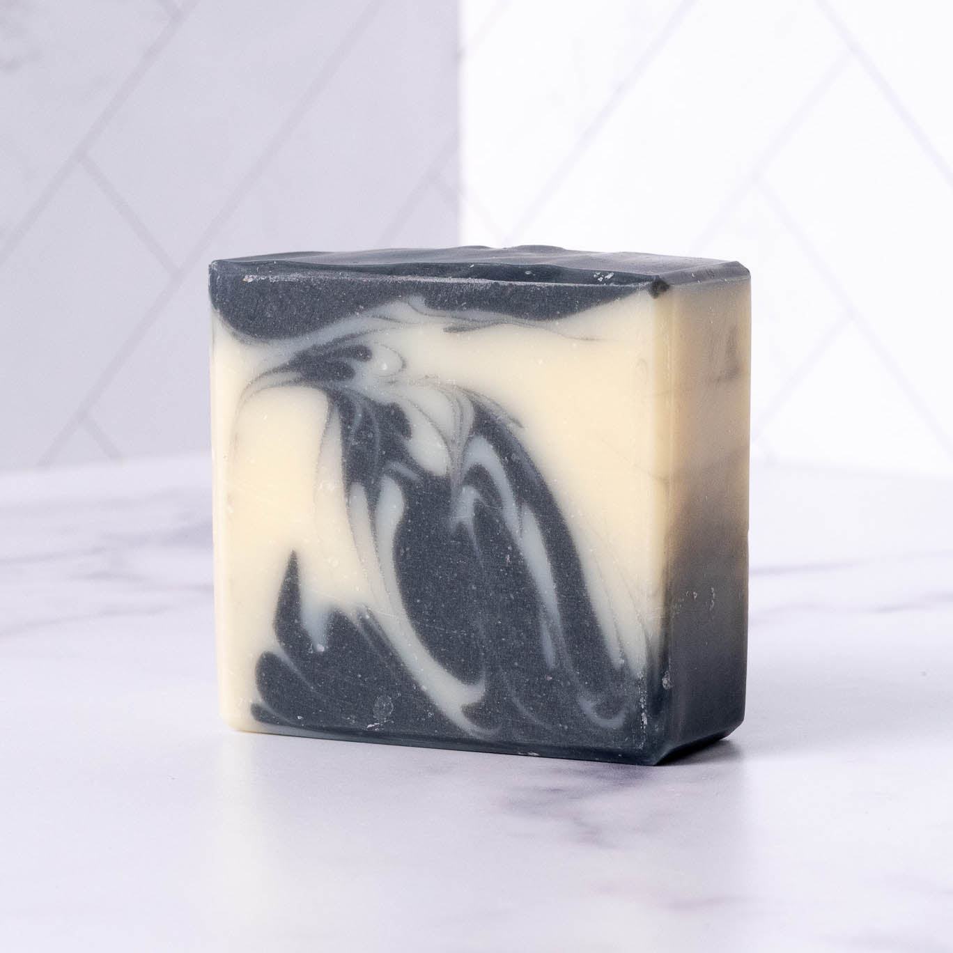 Black and white swirled charcoal soap bar on a light gray background