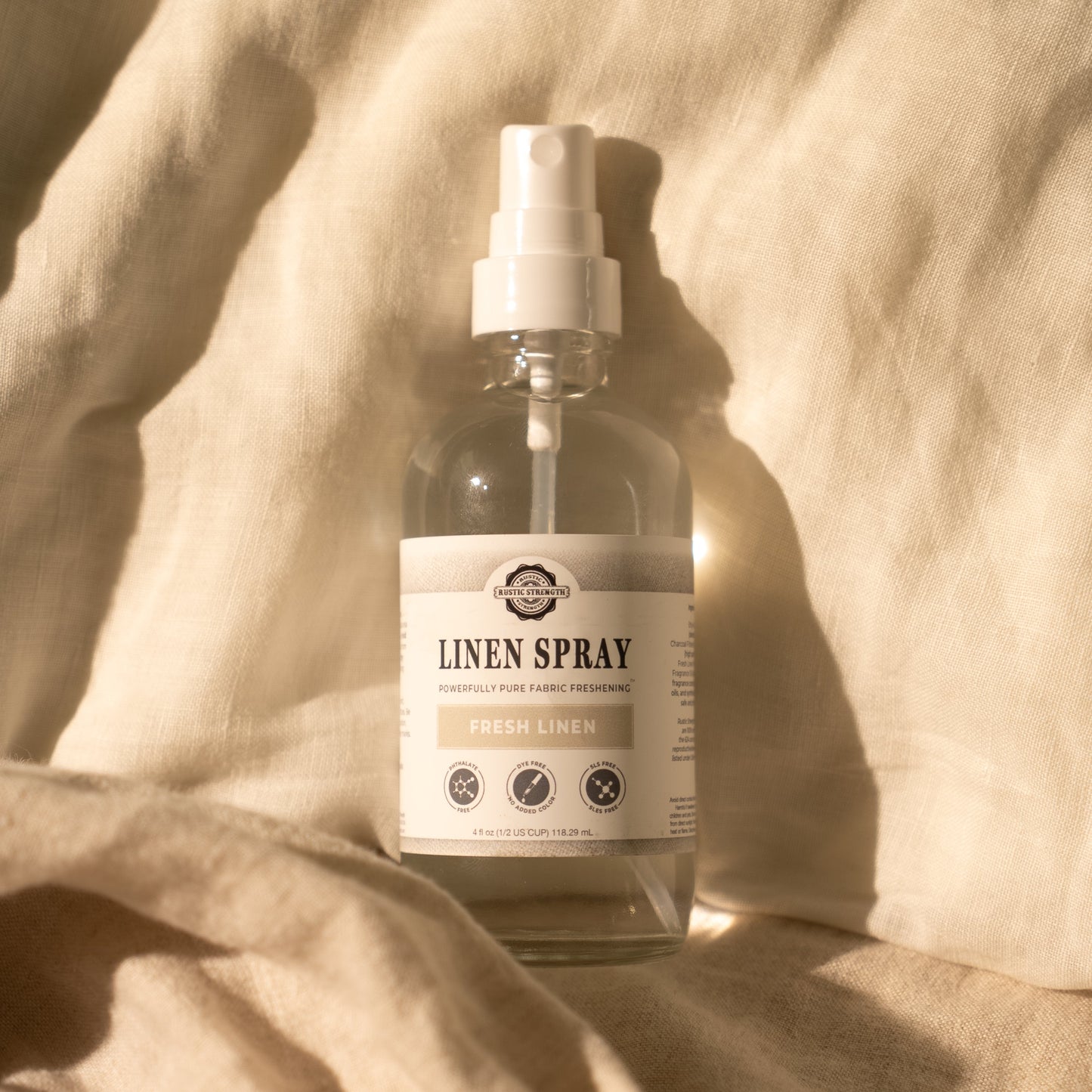 Bottle of Rustic Strength Linen Spray, Fresh Linen scented, on a textured beige fabric background