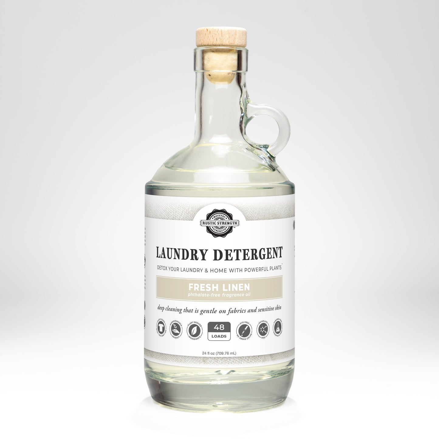 24oz glass bottle of Rustic Strength Liquid Laundry Detergent with a wooden cap on a white background