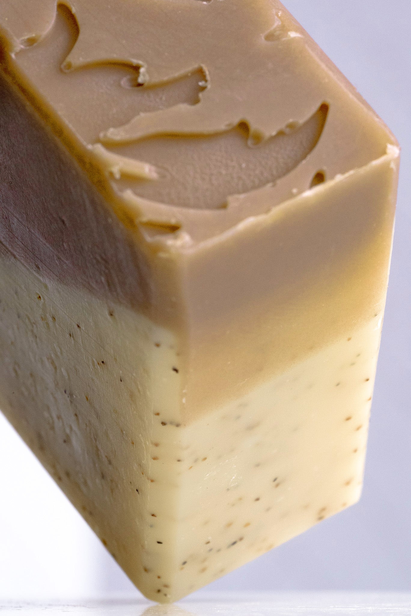 Close-up of a sandalwood patchouli bar of soap with a textured surface on a white background