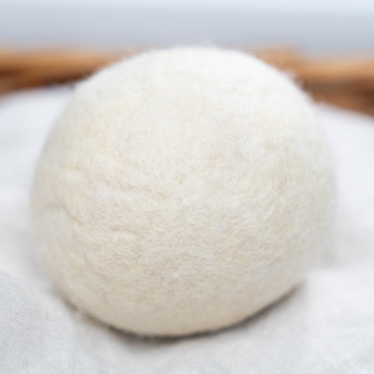 White wool dryer ball on a wooden surface with a blurred background