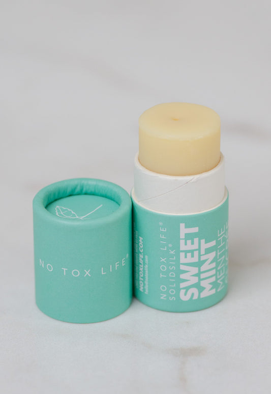 No Tox Life Sweet Mint Lip Butter stick with mint green paper container labeled 'No Tox Life' on a light gray background