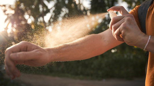 Person spraying insect repellant or after sun spray onto arm.