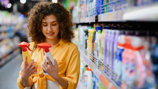 Person comparing eco-friendly household products and reading product labels to identify truly sustainable products in a modern kitchen.