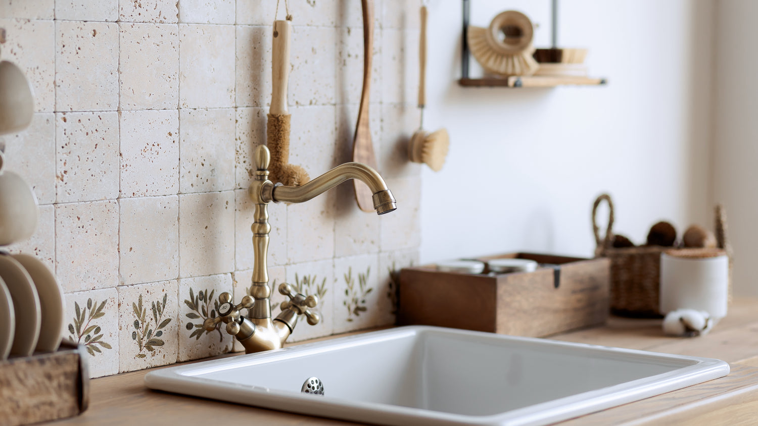 Brightly lit kitchen sink with ceramic tiles and wooden utensils.