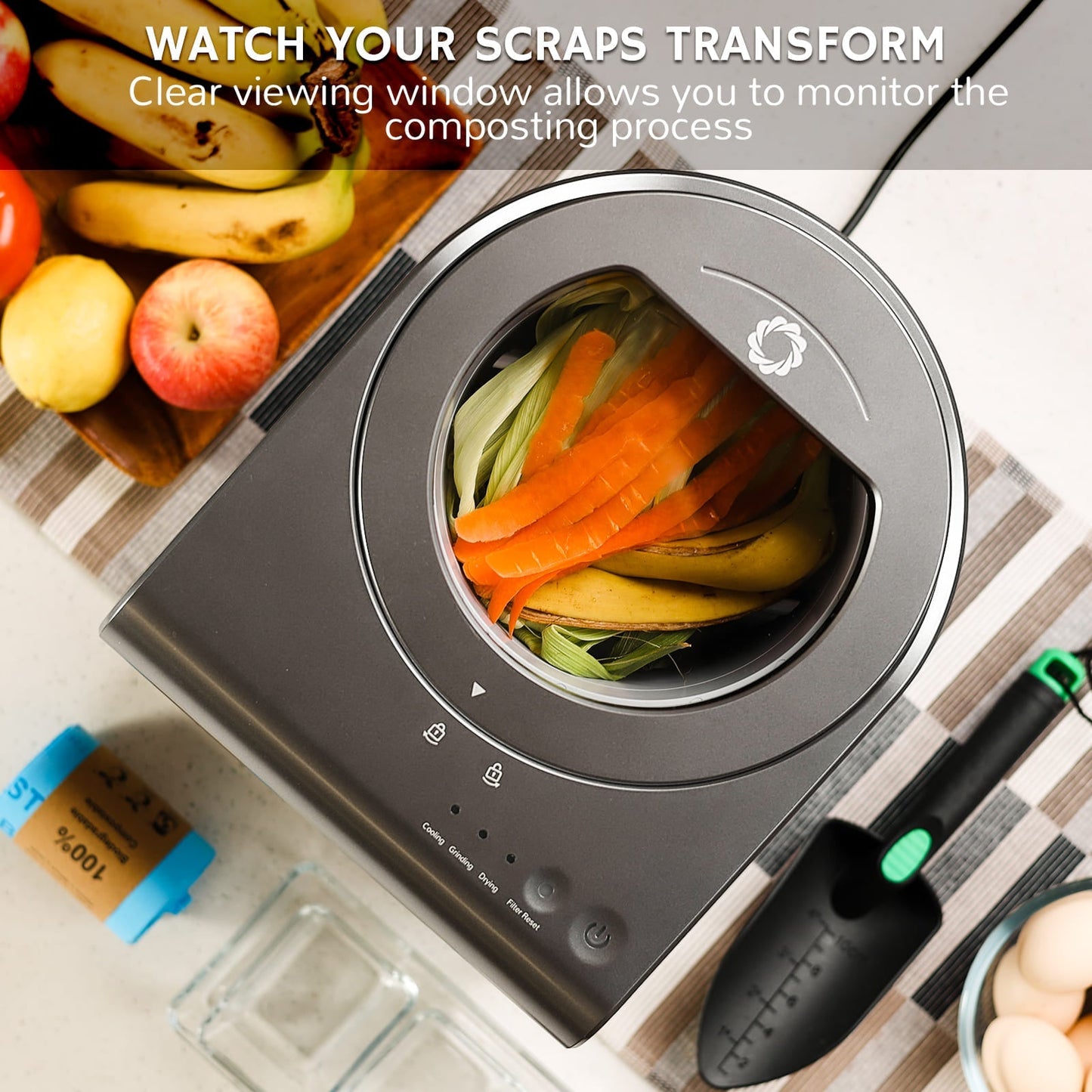 Airthereal electric composting bin with clear viewing window showing food scraps, surrounded by fruits and a garden tool.