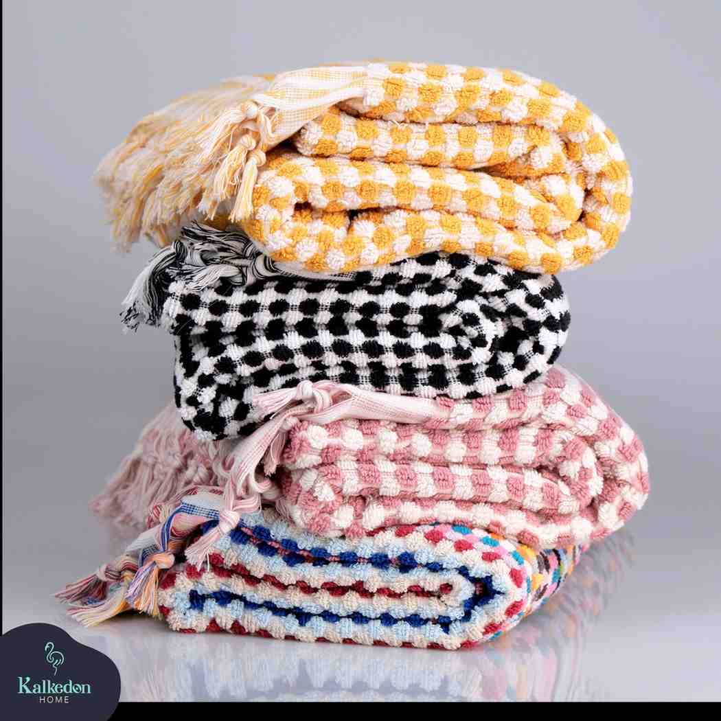 Stack of folded Premium Organic Turkish Jacquard Bath Towels – Oversized & Plush with colorful patterns on a gray background