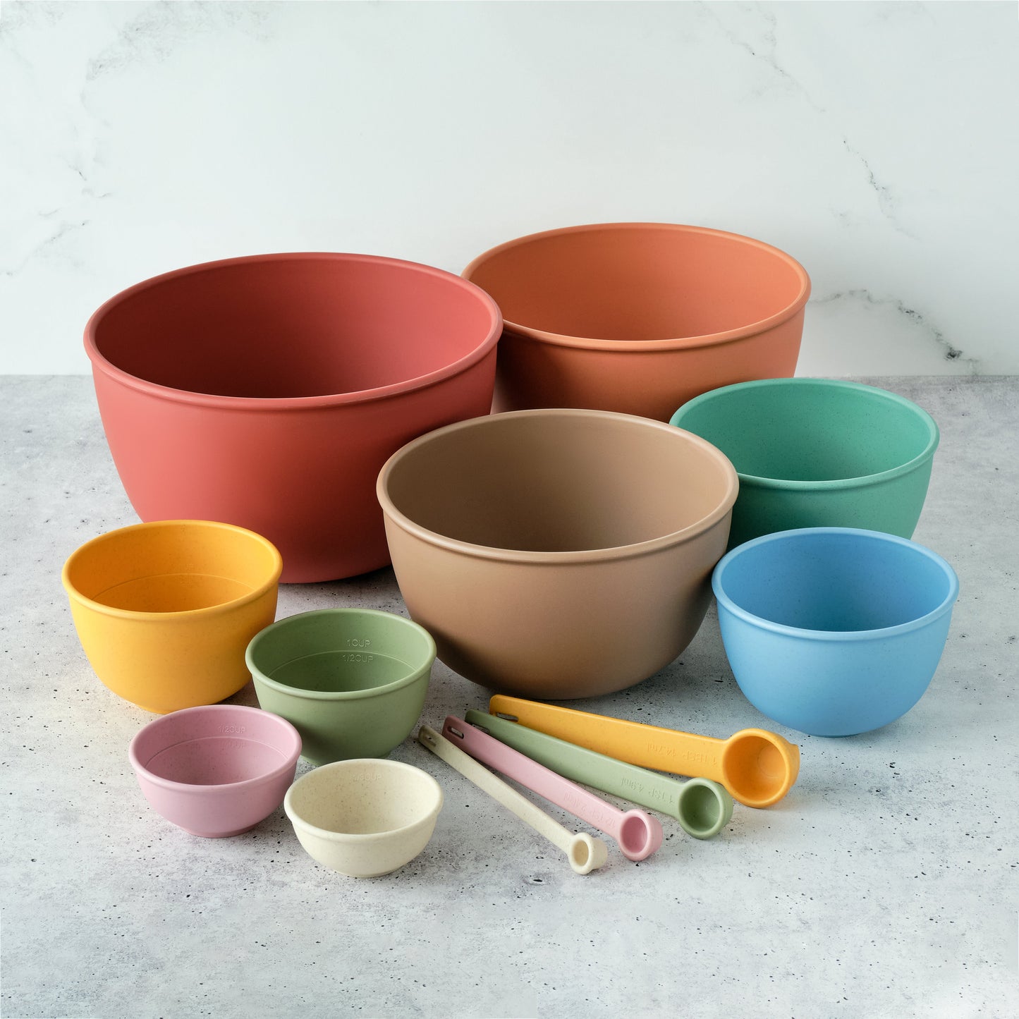 Set of Astrik desert bloom mixing bowls, measuring cups and spoons on a light gray surface