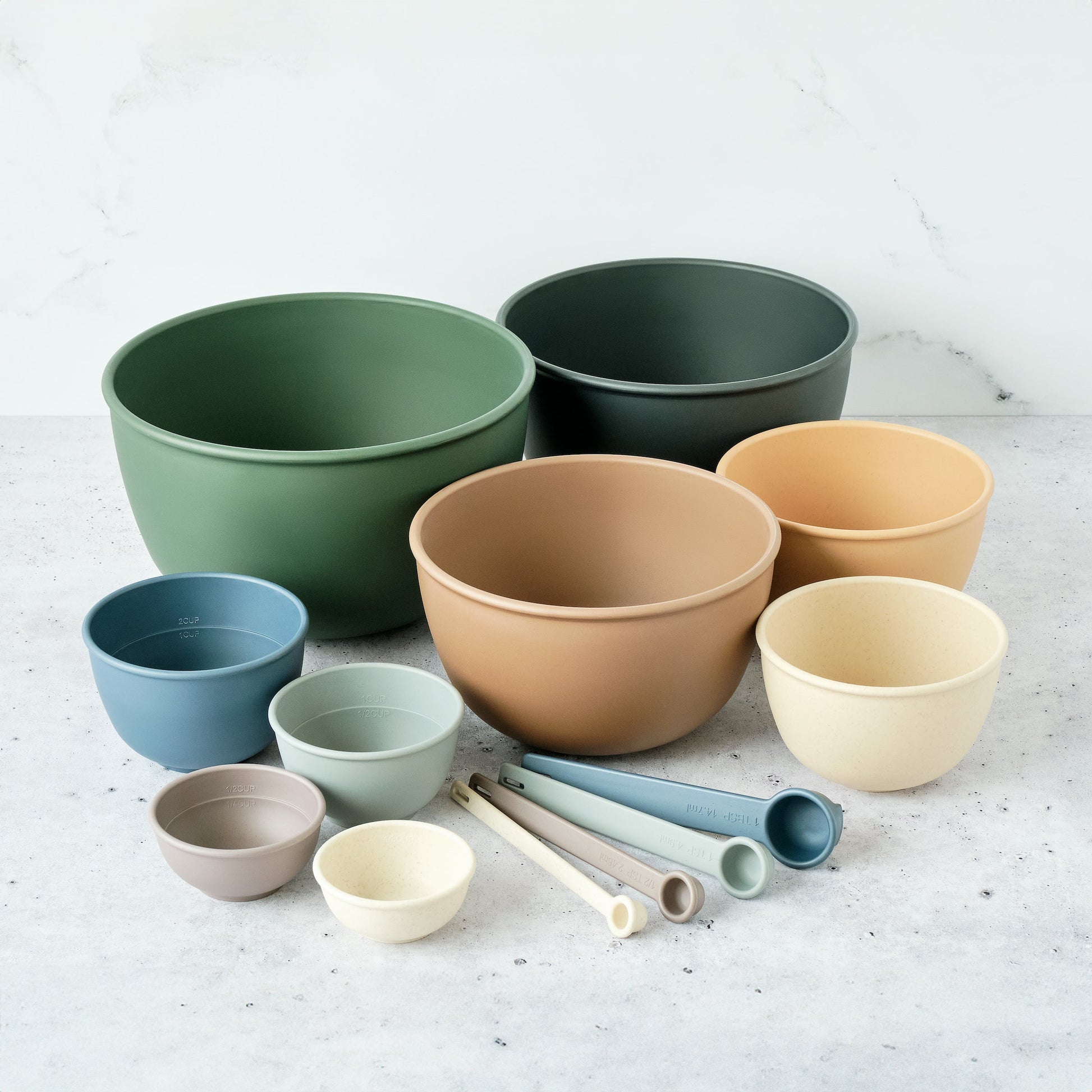 Set of eco-friendly, colorful Astrik mixing bowls, measuring cups and spoons on a light surface