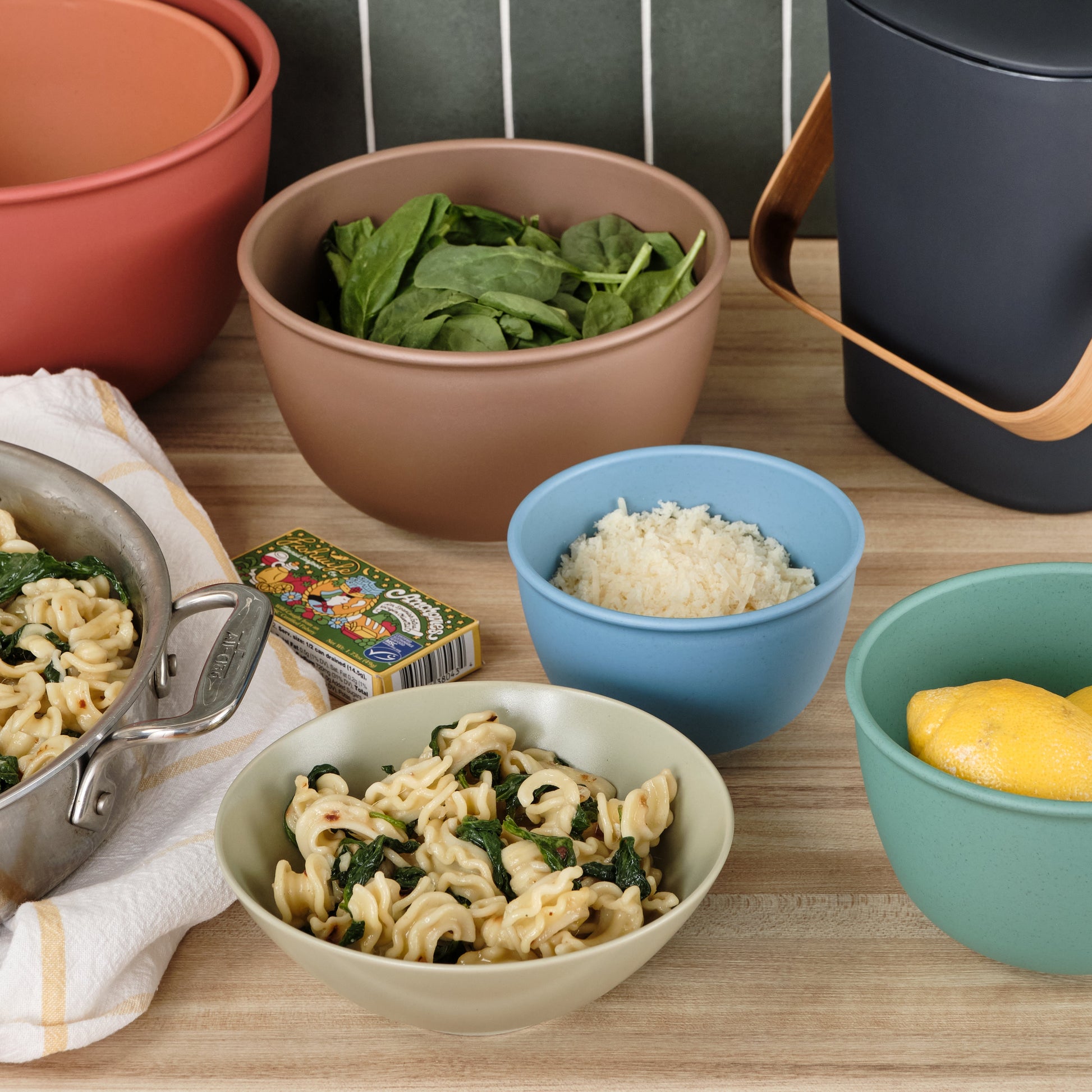 Table with various Astrik bowls and measuring cups containing different food items on a wooden surface.