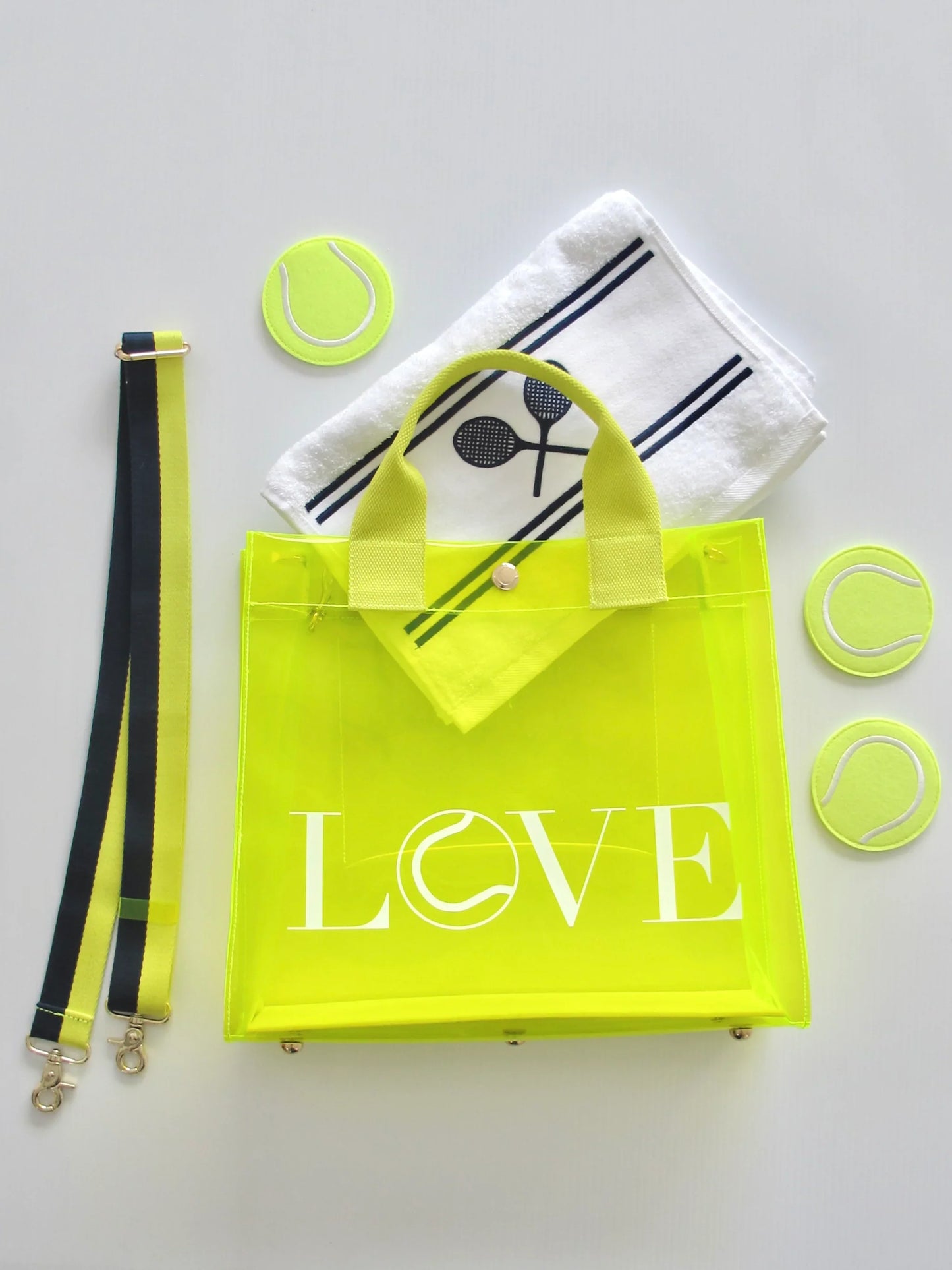 Biodegradable clear tote bag with structured design and reinforced seams. Yellow 'LOVE' bag with tennis-themed accessories on a light gray background