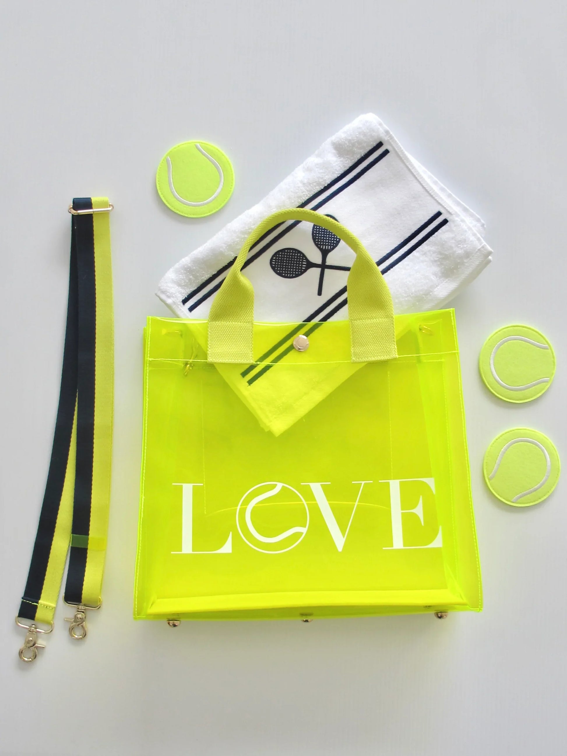 Biodegradable clear tote bag with structured design and reinforced seams. Yellow 'LOVE' bag with tennis-themed accessories on a light gray background