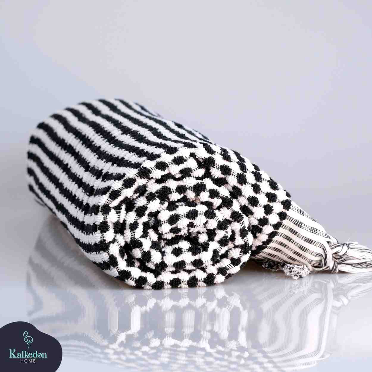 Black and white checkered Premium Organic Turkish Jacquard Bath Towel on a reflective surface with a light gray background