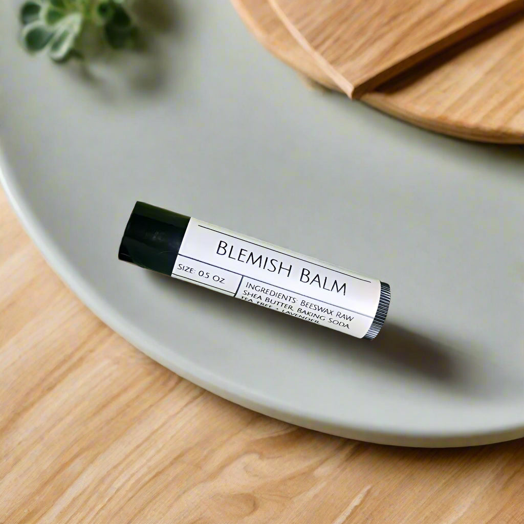Blemish balm all-natural spot stick tube for acne on a gray plate with a wooden surface and plant in the background