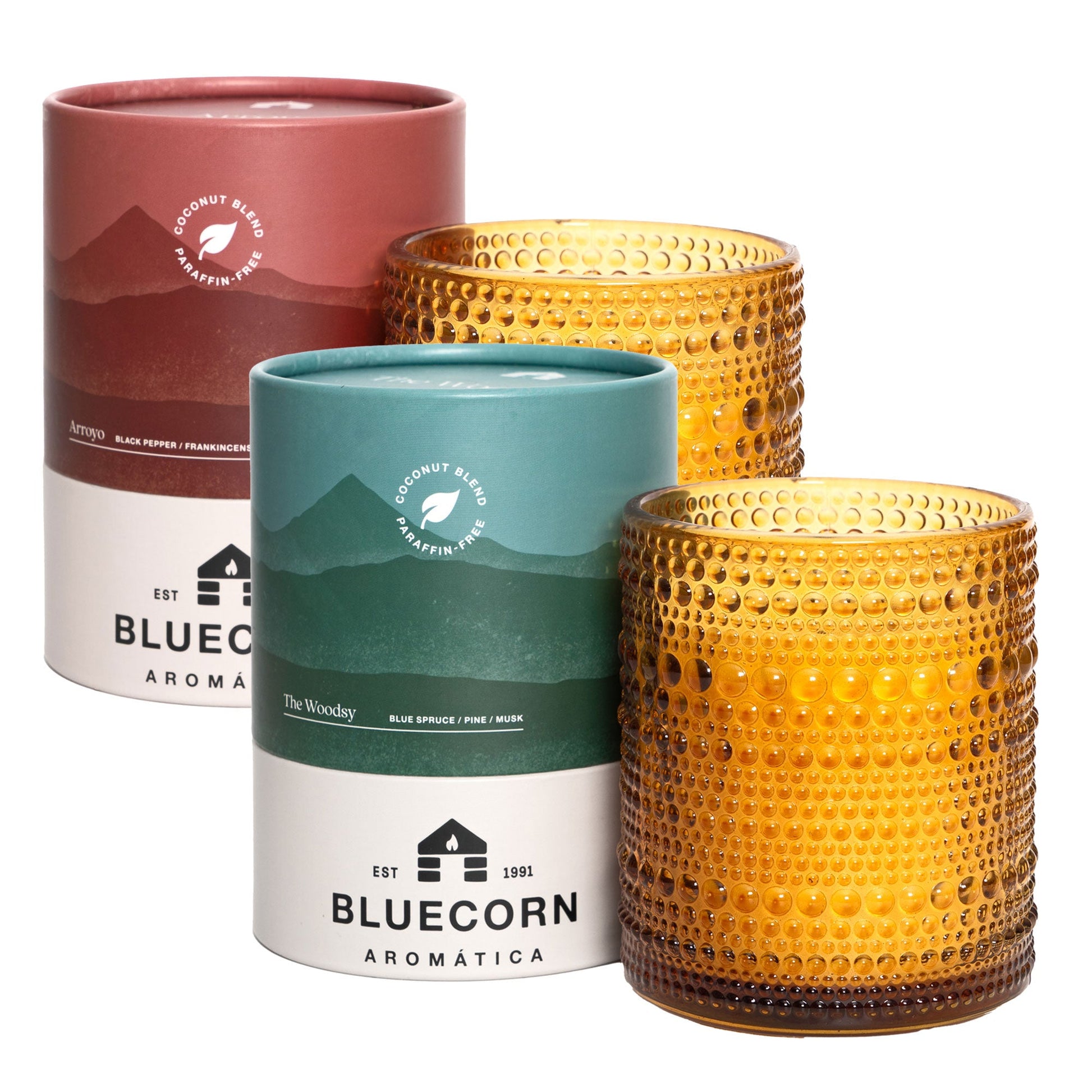 Bluecorn Aromatica Scented Candles Winter Scented pair of Pine and Spice, shown beside blue and red paper-based packaging on a white background.