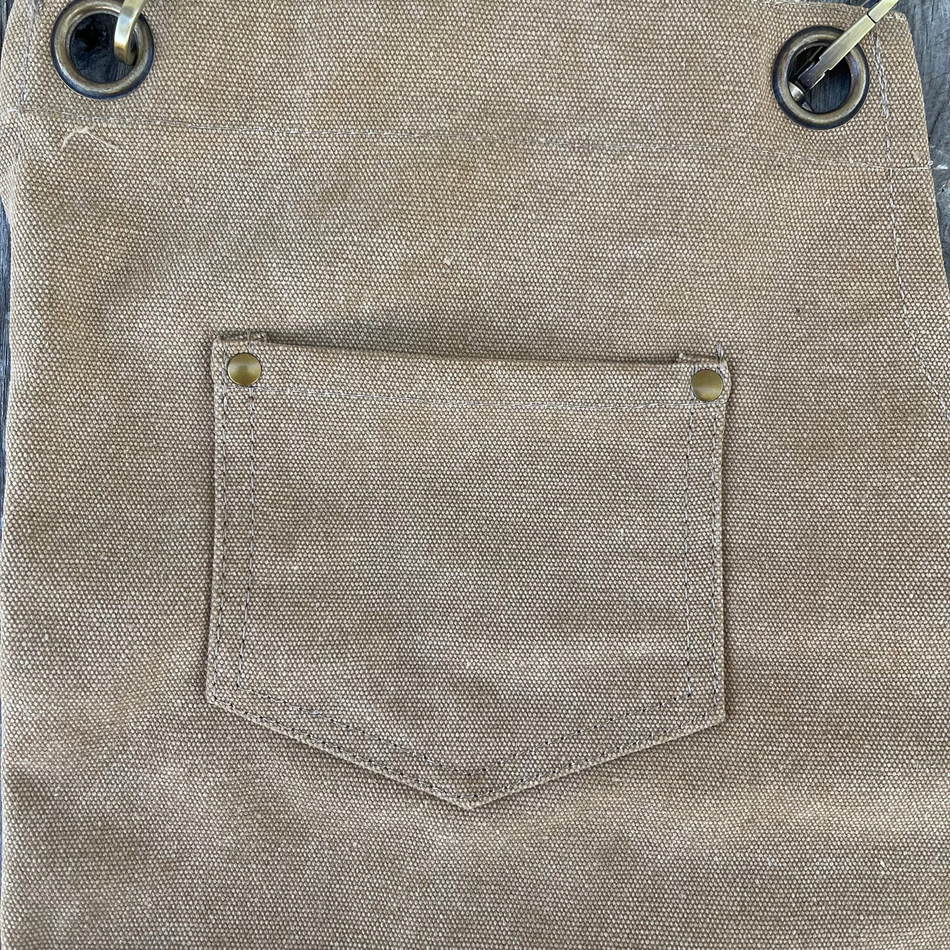 Close-up of a beige garden apron with a pocket and button details.