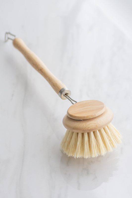 Eco-Friendly bamboo dish brush with a natural bristle head that is removable on a white background