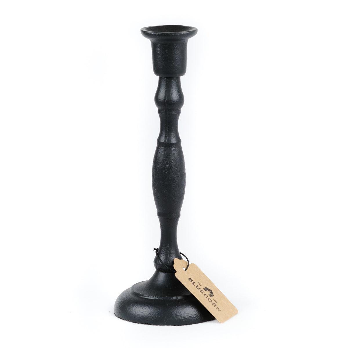Black cast iron candlestick holder with a tag on a white background