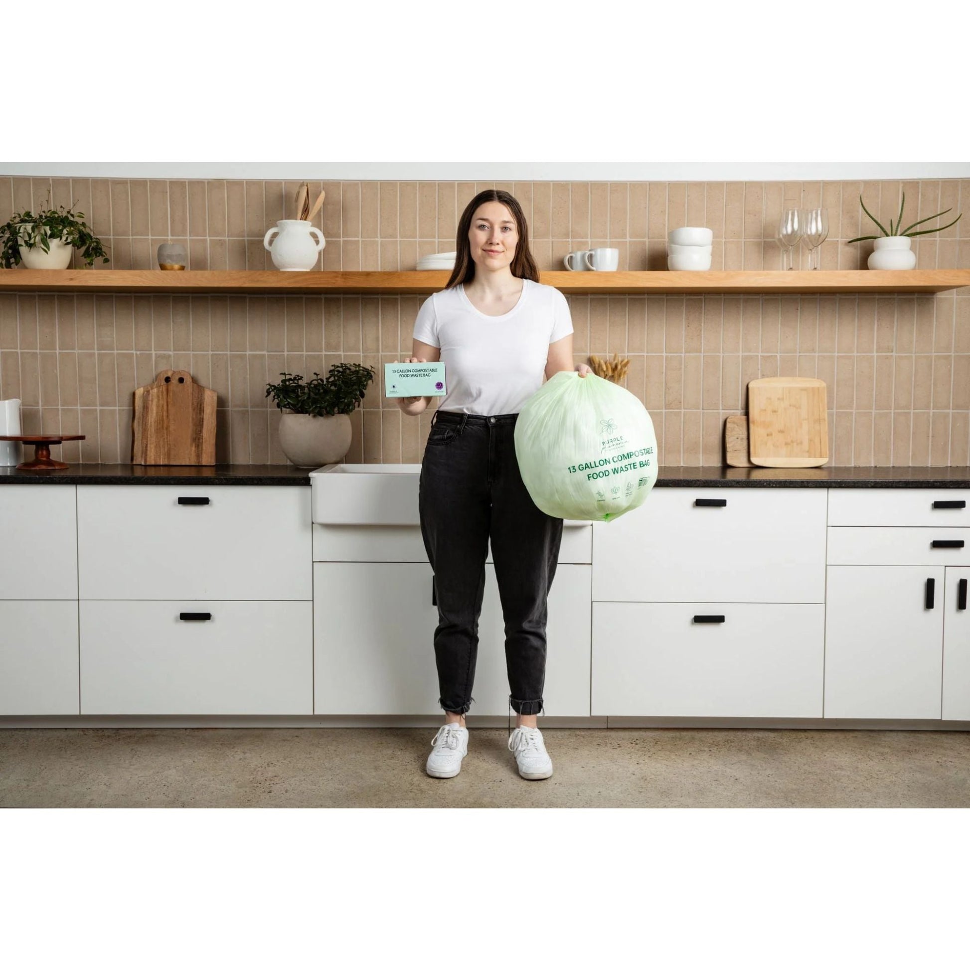 Person holding a large compostable food waste bag in a kitchen