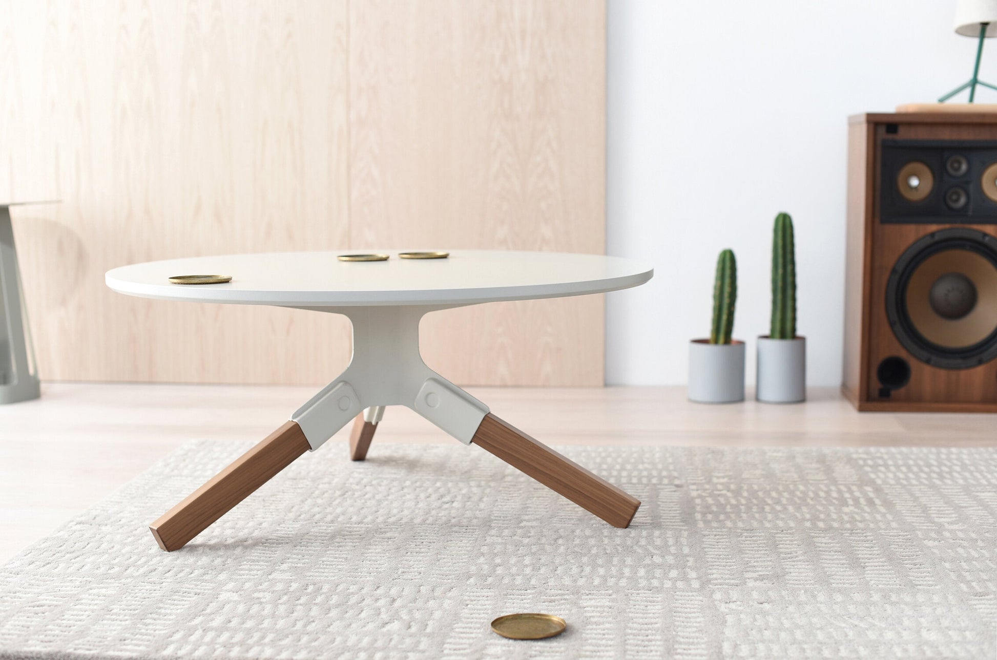 Conrad Coffee Table - Round modern table with white top and base, and wooden legs in a minimalistic room setting.