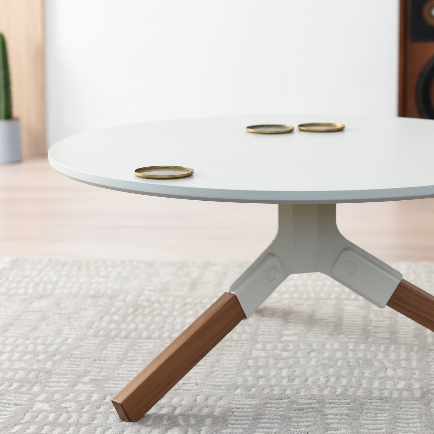 Conrad Coffee Table - Round table in London design with wooden legs and a white top in a room setting.