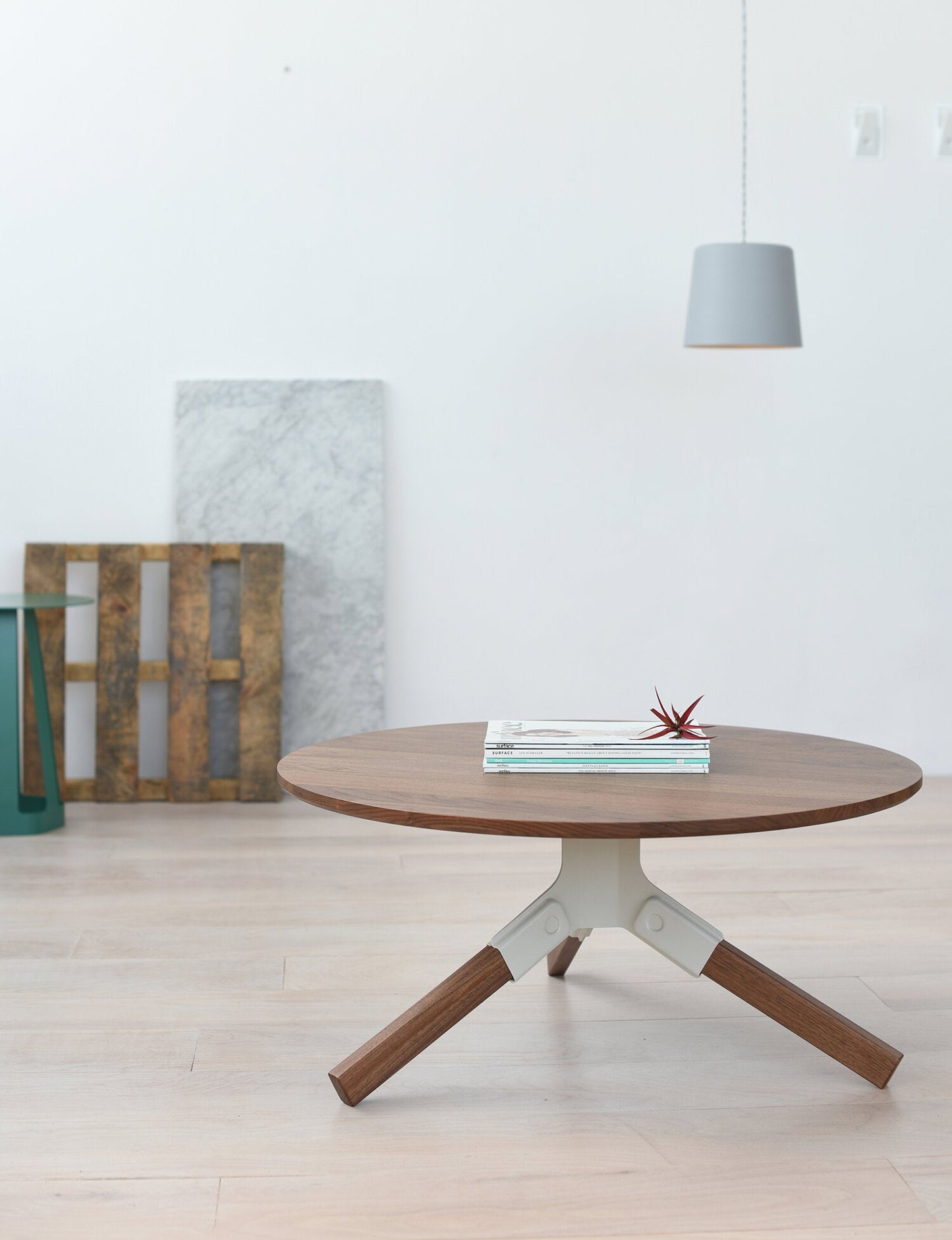 Conrad Coffee Table - Round wooden table with a white base in a minimalistic room.