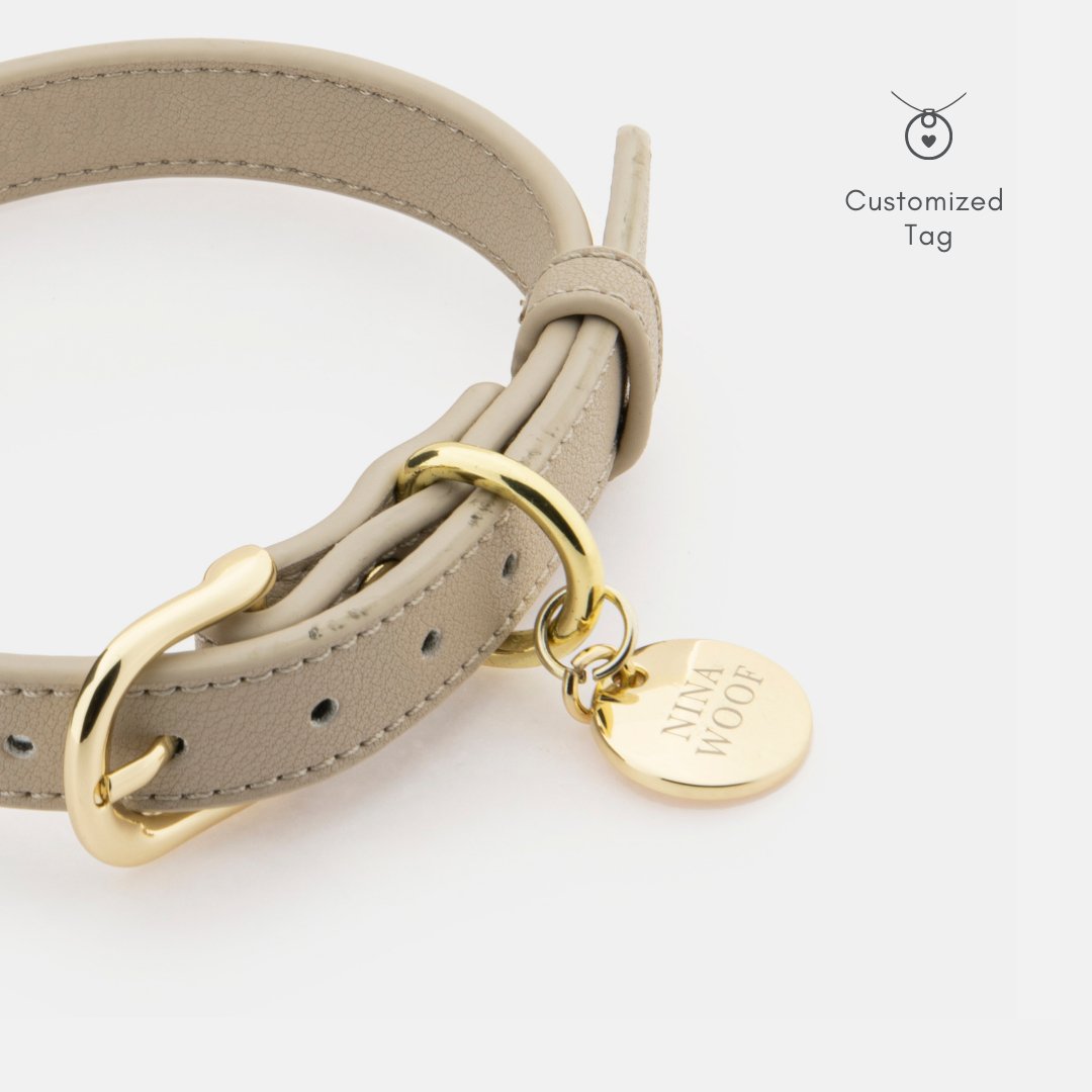 Beige Copenhagen Dog Collar made with recycled materials and PETA-approved soft vegan leather with gold reinforced hardware and a customizable tag on a white background